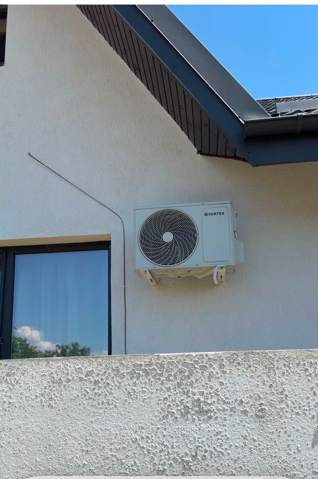 Unitate exterioară Vortex montată pe peretele unei case