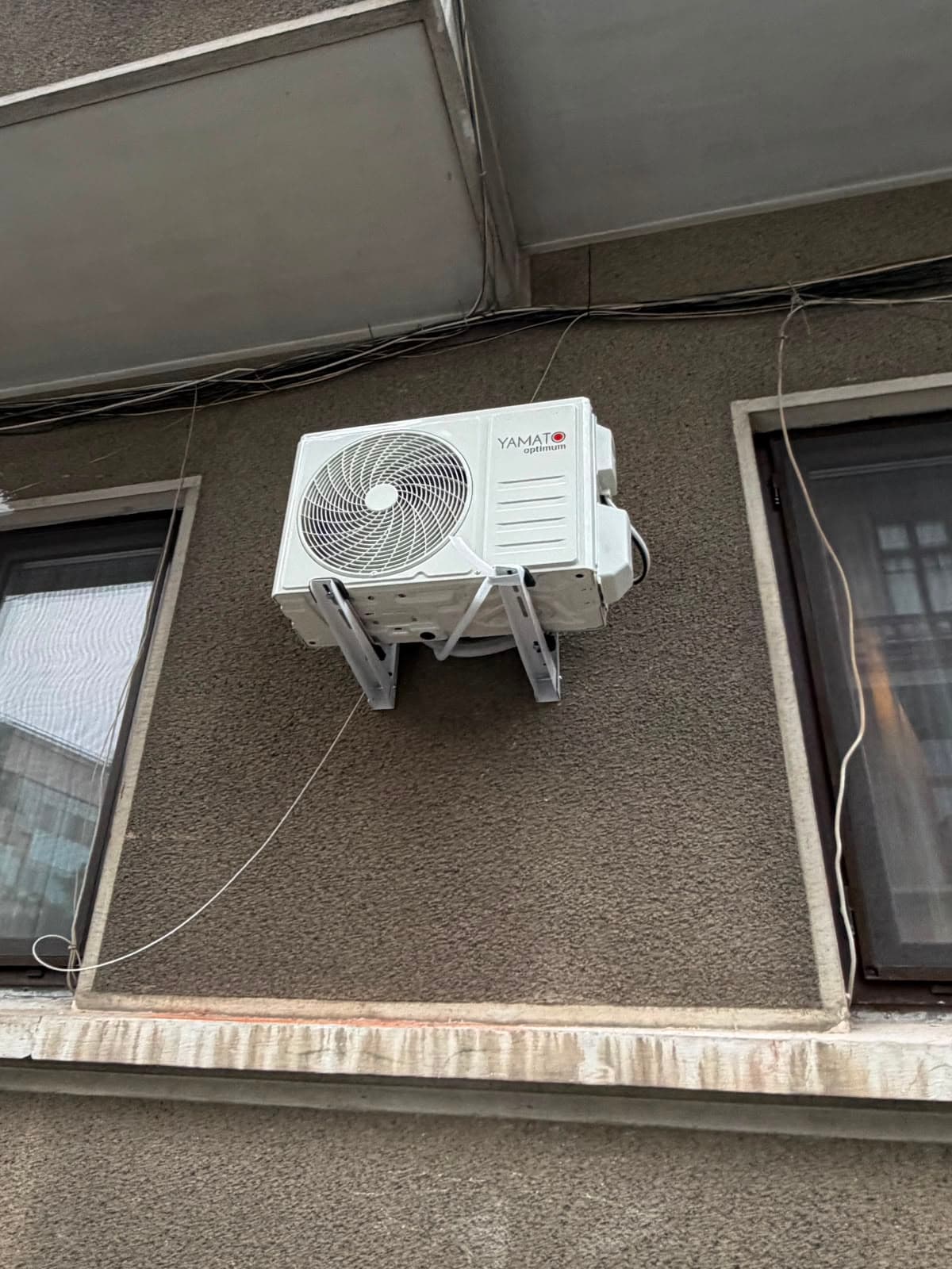 Unitate exterioară Yamato montată pe fațada unui bloc, pe suporți metalici